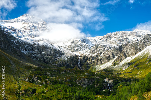 Mountain with waterfalls and a transition from a green forest to a snow area