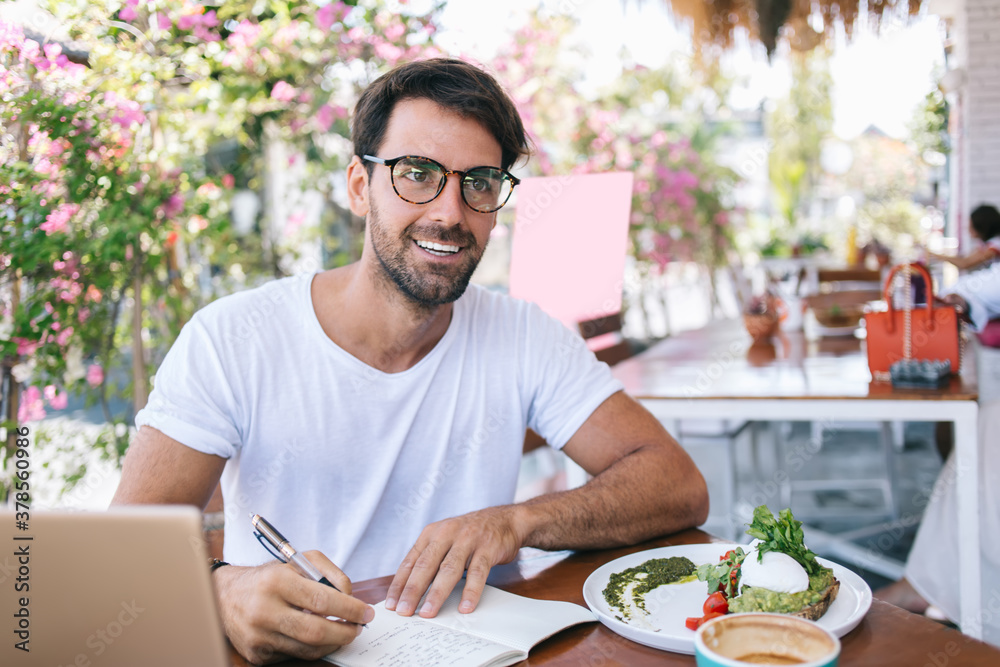 Smiling man writing notes in planner