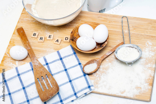 making dough for bread or homemade baked goods. ingredients on a wooden table. inscription: bread