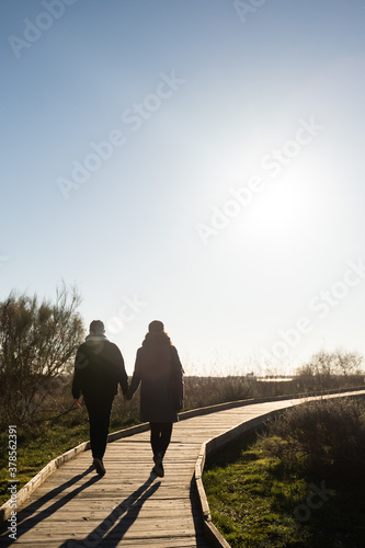Young beautiful couple holding hands walking along a wooden walkway in the natural park of 'Las lagunas de Ruidera'. Lagoons in Ossa de Montiel, Albacete, Spain.
