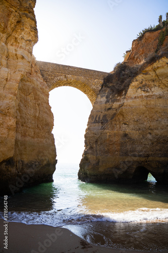 Sandy beach with an arched bridge surrounded by cliffs called  Praia dos Estudantes . Lagos  Algarve  Portugal.