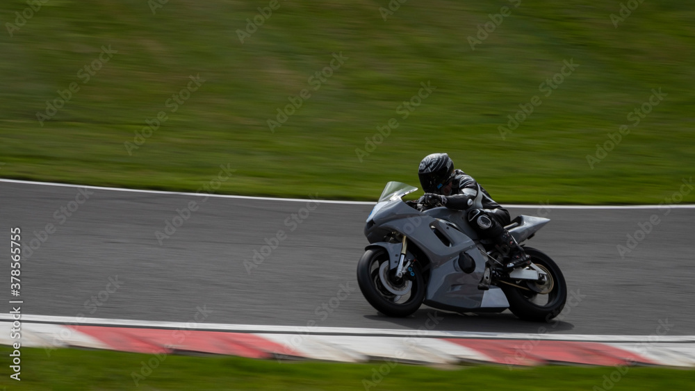 A panning shot of a racing bike cornering as it circuits a track.