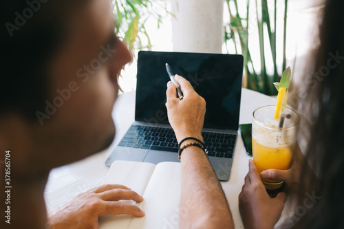 Unrecognizable couple working on laptop and pointing at screen