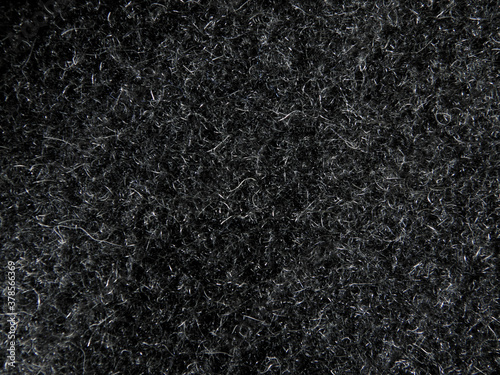 Black natural wool carpet texture background. Texture of dark wool fabric. fragment of a grey furry coat