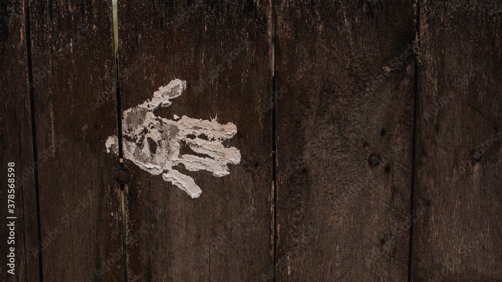 white palm and fingerprint on the Old shabby wooden grey boards. fence. background. texture. Weathered painted plank. Vintage. wall. paint. Hand in white paint. white palm and fingerprint on the Old shabby wooden grey boards. fence. background. texture. Weathered painted plank. Vintage. wall. paint. Hand in white paint.