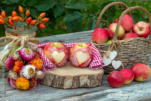 Rote Äpfel mit Herz rustikal auf Holz als Dekoration für den Herbst