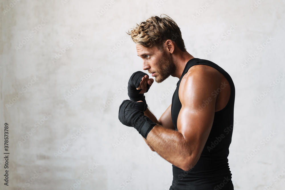 Photo of athletic young handsome boxer doing exercise while working out