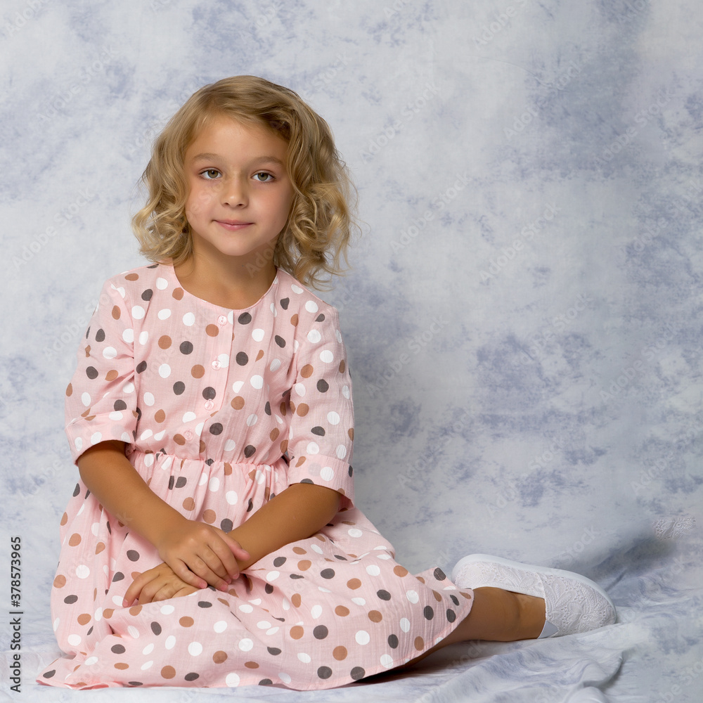 Fototapeta premium Little girl is sitting on the floor.The concept of a happy childhood.