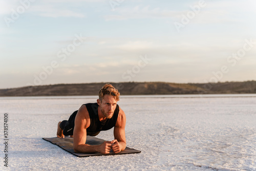Photo of athletic young sportsman doing exercise while working out