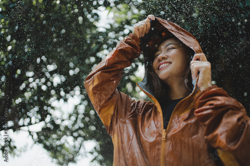 Asian woman is outdoors while it s raining. She felt refreshed.