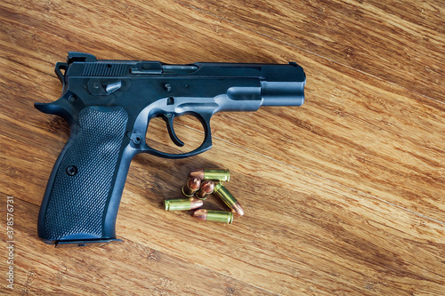 A semiautomatic 9mm pistol with 9mm bullets on a brown wood background photo