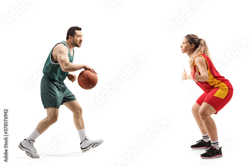 Full length profile shot of a young male and female basketball players playing basketball