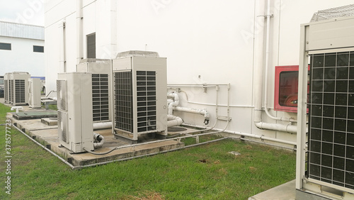 Close up Air conditioning out door,A group of three industrial sized air conditioners along a brick wall,Air conditioning with extra door for maintenance