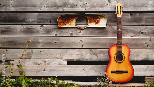 Acoustic guitar leaning against weathered boards © Kevin Brine