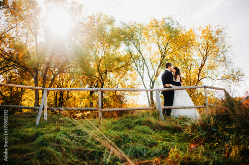 Newlyweds kissing on the background of the autumn forest.