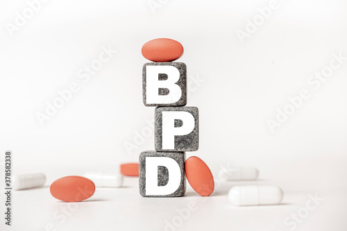 a group of white and red pills and cubes with the word BPD: Borderline personality disorder on them, white background. Concept carehealth, treatment, therapy.