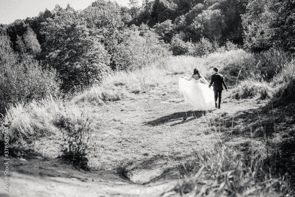 Black and white photo of newlyweds in the park running holding hands.