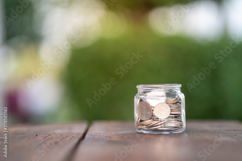Money saving, Hand putting coin in glass jar with coins inside For now and future 