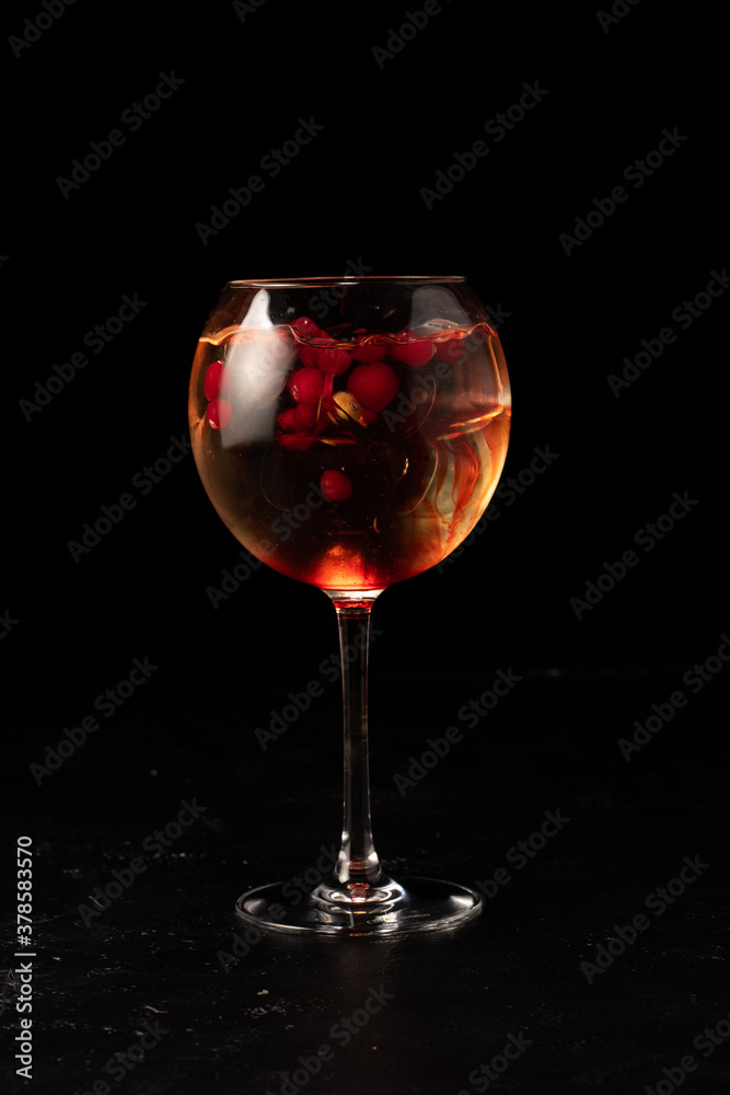 Alcoholic cocktail with cranberries and berry syrup in a transparent glass on a dark background Alcoholic cocktail with cranberries and berry syrup in a transparent glass on a dark background