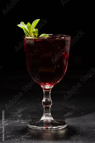 Glass of red wine sangria with mint leaves on black background