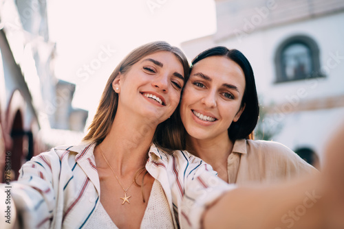 Selfie portrait of cheerful Caucasian hipster girls smiling at camera during touristic vacations for together recreation, close up of happy female friends feeling satisfied for video posing