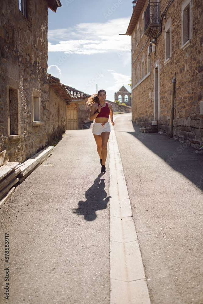 Female athlete running on rural village. Runner exercison on road mountain.