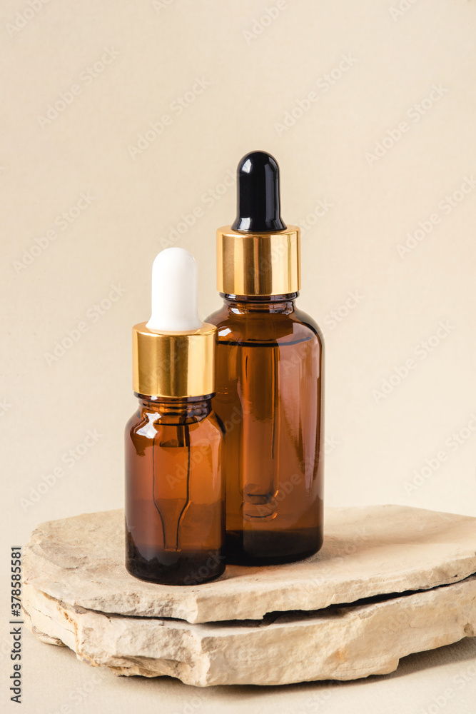 Naklejka premium Two brown bottles of cosmetics on a natural beige background. Stone podium. Front view.