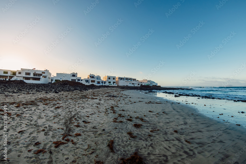 Famara beach and Caleta de Famara town with cold sunset tones in Lanzarote, Canary islands