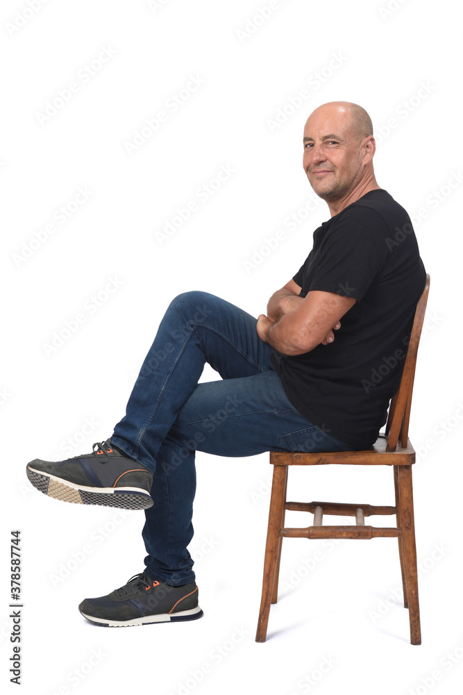 full portrait of a bald man sitting sideways on white background, arms and legs crossed full portrait of a bald man sitting sideways on white background, arms and legs crossed