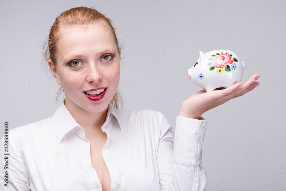 Young red haired woman with her piggy bank / porcelain bank Young red haired woman with her piggy bank / porcelain bank