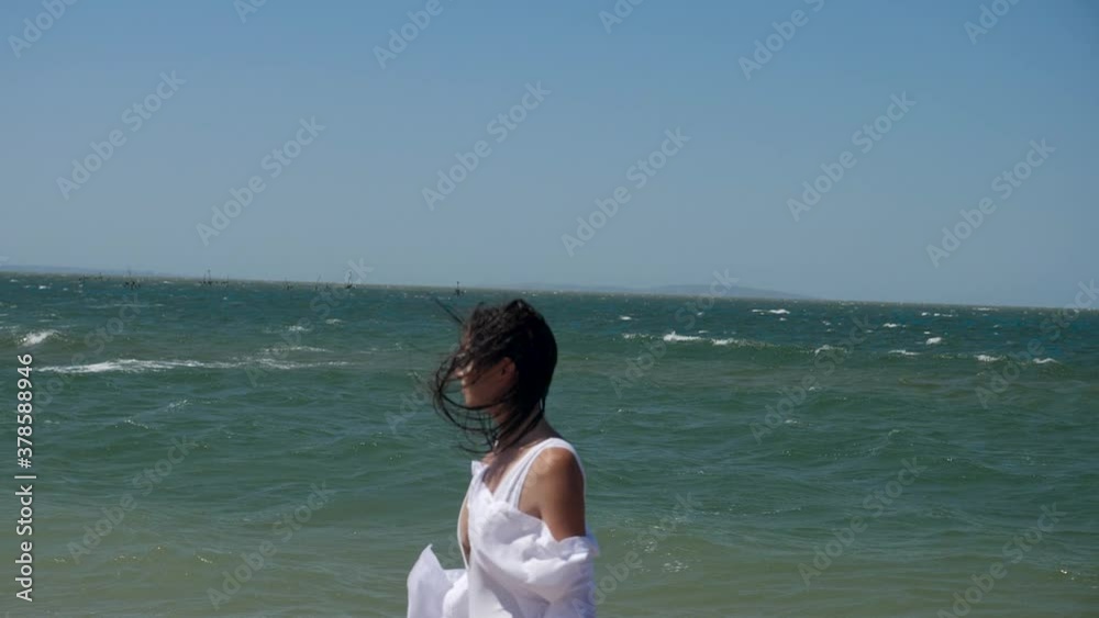 brunette woman in a white swimsuit walks along a sandy beach by the sea in summer brunette woman in a white swimsuit walks along a sandy beach by the sea in summer