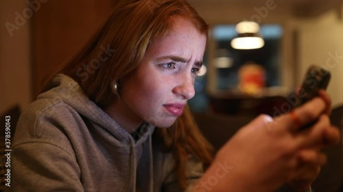 junge Frau schreibt wütend auf ihrem Smartphone, das Gesicht wird vom Display angeleuchtet