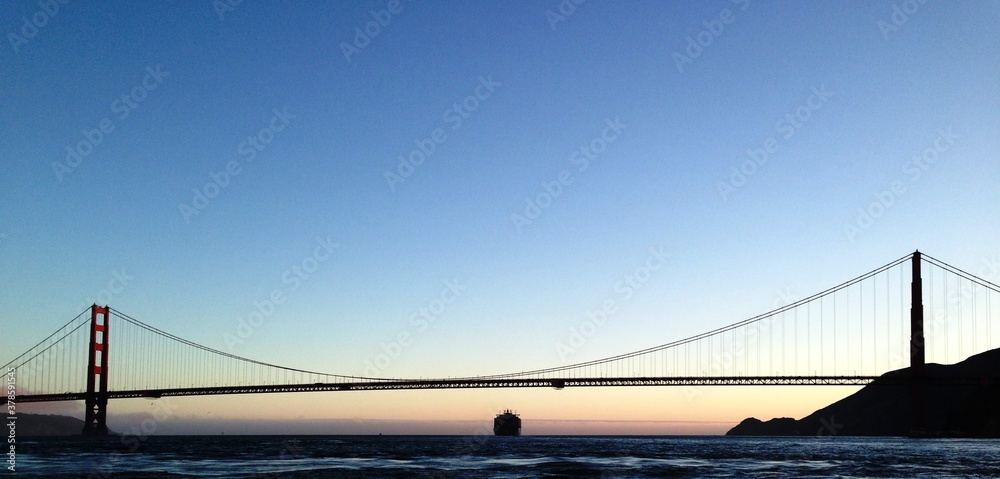 Golden Gate Bridge at sunset with boat passing underneath, San Francisco California Golden Gate Bridge at sunset with boat passing underneath, San Francisco California