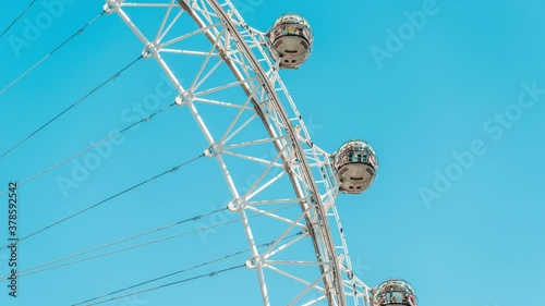 Timelapse, time lapse of closeup view on London Eye on summer day, blue clear sky, people riding in capsules on Cantilevered observation wheel in UK