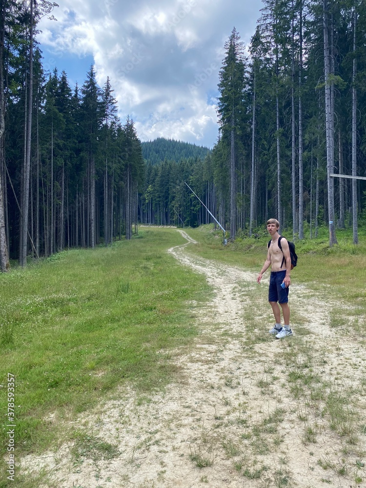 The man on the road in the forest. The guy is walking in the forest on the road. the man is hiking in the mountains The man on the road in the forest. The guy is walking in the forest on the road. the man is hiking in the mountains
