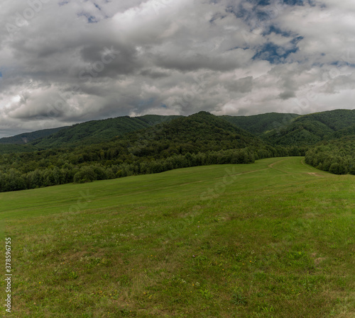 Panorama view with meadows and pasture land and gray clouds near Runina village