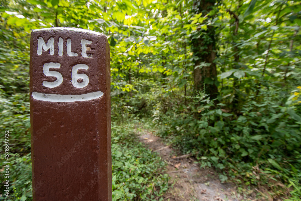mile post sign along path in the woods near a canal mile post sign along path in the woods near a canal