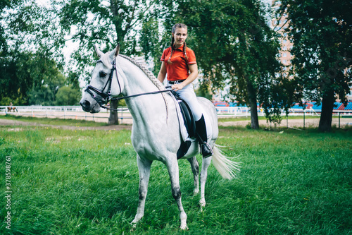 Portrait of professional female jockey practising horseback equitation riding and looking at camera during free time in country club, concept of equestrian sport and friendship with animal © BullRun