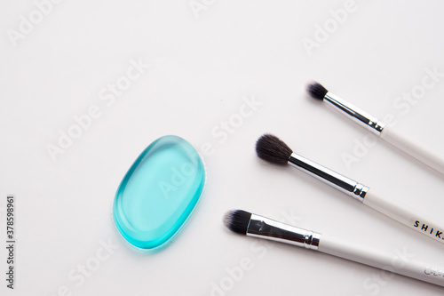 Professional makeup brushes and light background transparent drop of soap cosmetics