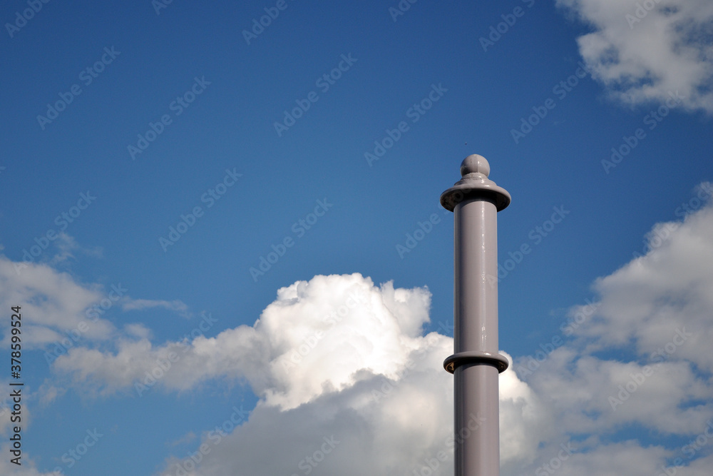 Tall Grey Iron Post against Blue Sky with White Clouds Tall Grey Iron Post against Blue Sky with White Clouds