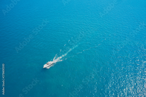 Large white boat with a blue awning fast movement on blue water in the sun. Lonely boat movement on the water. Side view of the speed boat.