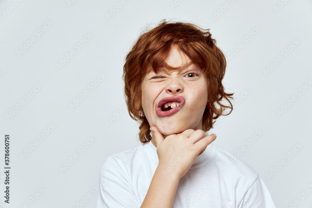 emotional redhead boy grimacing gray background studio 