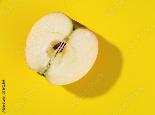 half of apple on yellow background