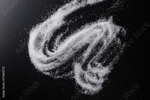 A scattering of white sugar on a black background