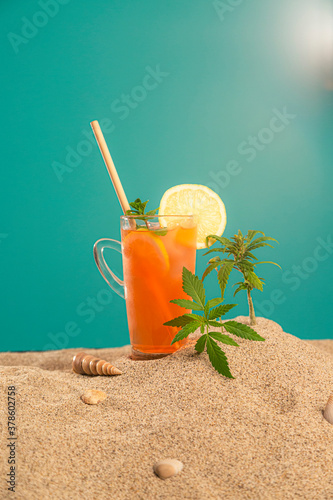 Product of CBDa oil, orangeade or ice tea in a jar and seashell on sand