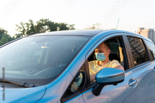 Middle aged man in protective sterile medical mask driving car. 