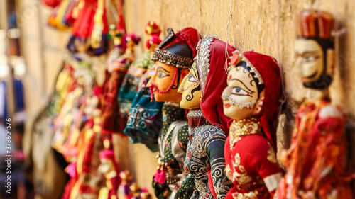 Colorful human face shaped Puppets wearing colorful clothes hanging against the wall in Rajasthan India on 21 February 2018 photo