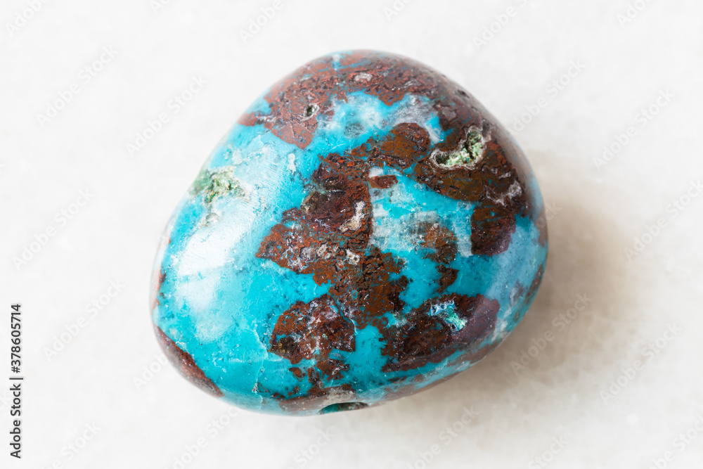closeup of sample of natural mineral from geological collection - tumbled Chrysocolla with Cuprite rock on white marble background closeup of sample of natural mineral from geological collection - tumbled Chrysocolla with Cuprite rock on white marble background