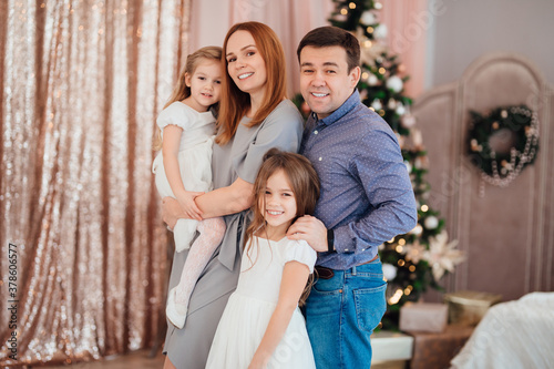 mom, dad and daughters at the Christmas tree. happy family on new year's holidays. festive mood. © andrey