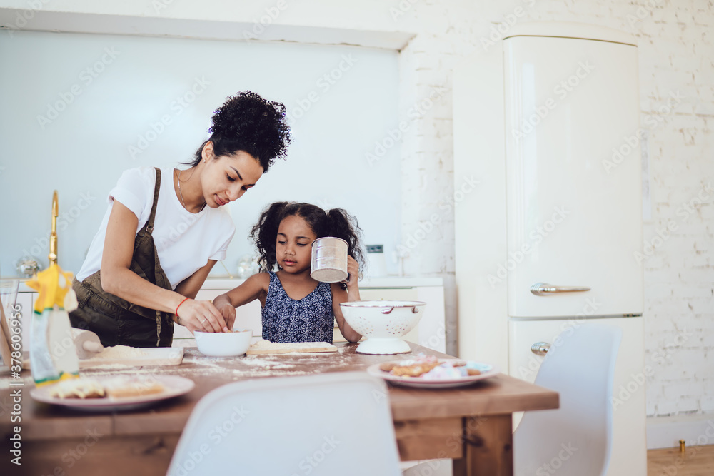 Young woman cooking with small daughter in kitchen at home Young woman cooking with small daughter in kitchen at home